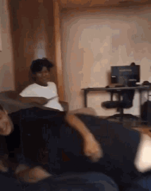 two people are sitting on a couch in a room with a computer in the background .