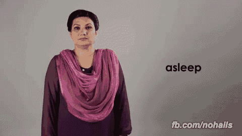 a woman wearing a purple scarf is making a sign that says asleep