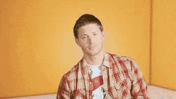 a man in a plaid shirt is giving a thumbs up .