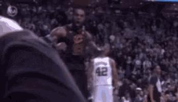 a basketball player is standing in front of a crowd and shouting at the camera .