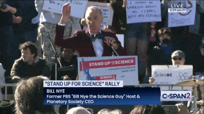 a man in a tuxedo stands in front of a podium that says " stand up for science "