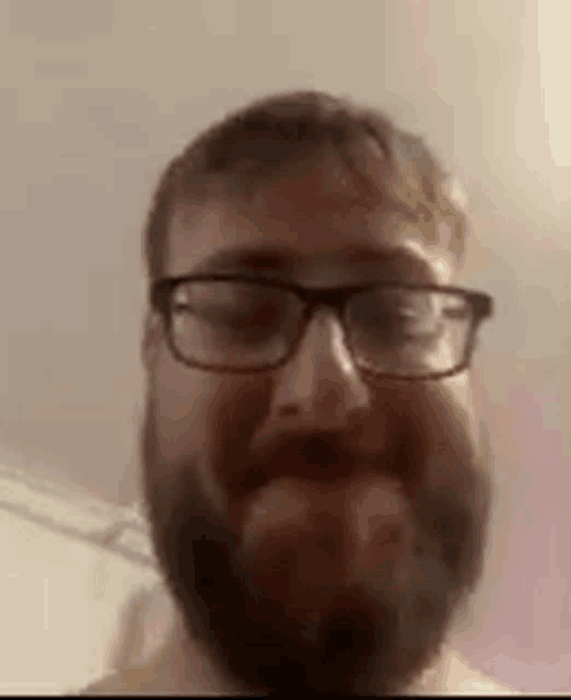 a man with a beard and glasses is smiling .