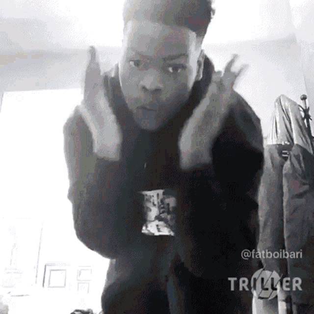 a man in a black hoodie is making a devil horns sign