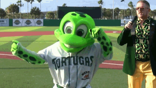 a man in a green jacket stands next to a mascot wearing a shirt that says tortugas