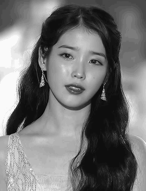a black and white photo of a woman wearing a white dress and earrings