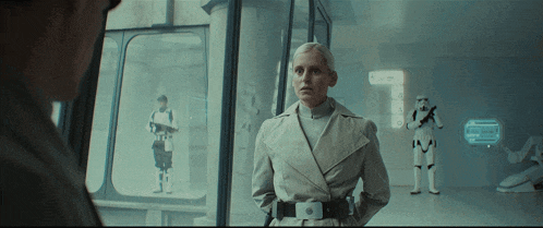 a woman in a trench coat stands in front of storm trooper soldiers