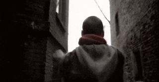 a man is walking down a narrow alleyway between two buildings .