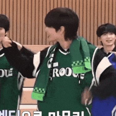 a group of young men are standing next to each other on a basketball court wearing green jerseys .