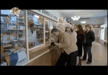 a group of people are standing in front of a pharmacy counter with a sign that says ' avangard '