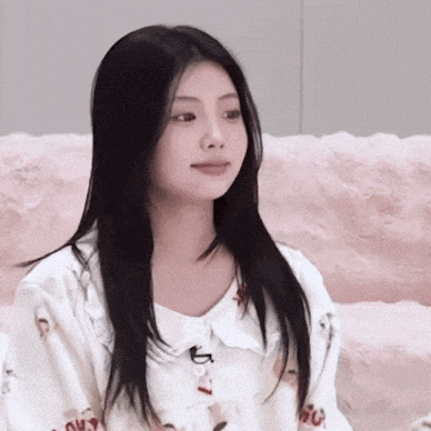 a woman with long black hair is sitting on a pink couch wearing pajamas .