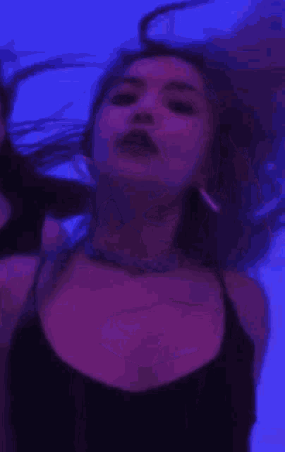 a woman in a black top is standing in front of a blue background .