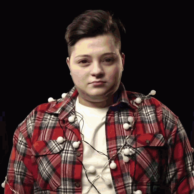 a man wearing a plaid shirt has christmas lights hanging from his shoulder