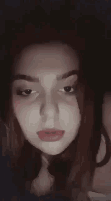a close up of a woman 's face in a dark room with a shadow on her face .