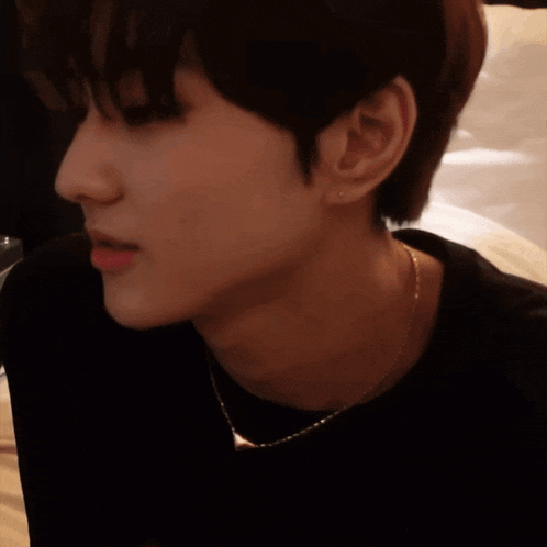 a close up of a person wearing a black shirt and a gold chain around their neck