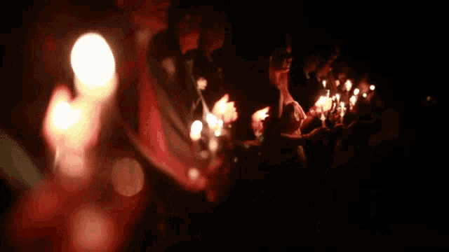 a group of people are holding lit candles in a dark room