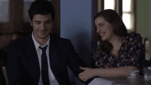 a man in a suit and tie sitting next to a woman who is smiling