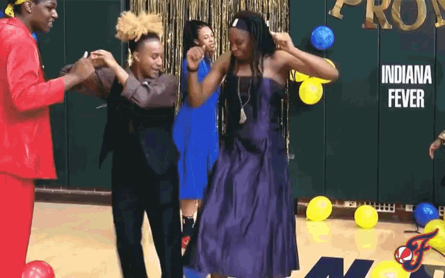a group of people are dancing in front of a wall that says indiana fever