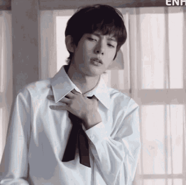 a young man in a white shirt and tie is adjusting his tie .
