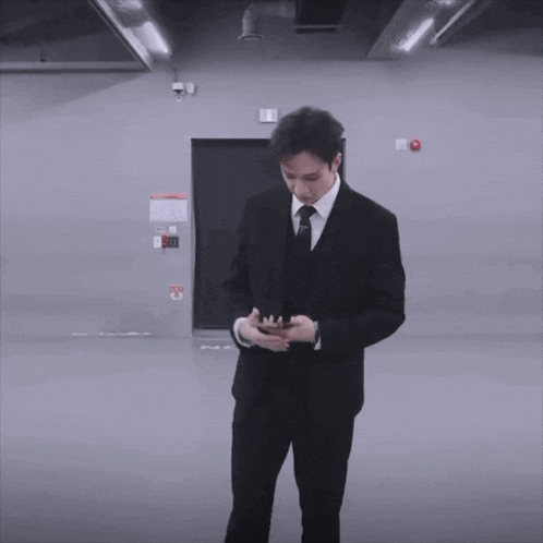 a young man in a suit and tie is standing in a room .