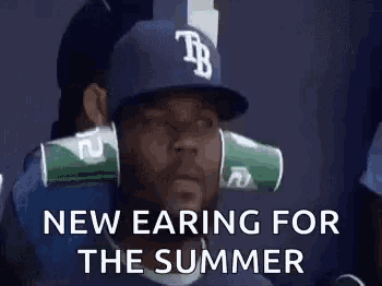 a man wearing a baseball cap with cups on his ears and the words `` new earring for the summer '' .