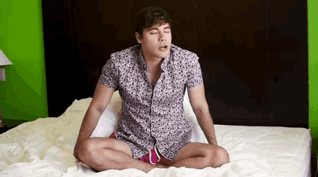 a man is sitting on a bed with his legs crossed