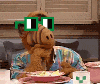 a stuffed animal wearing sunglasses is sitting at a table with a bowl of food