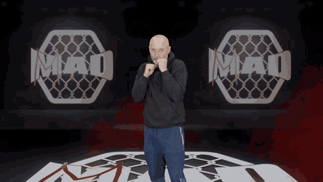 a man stands in front of a logo for mad