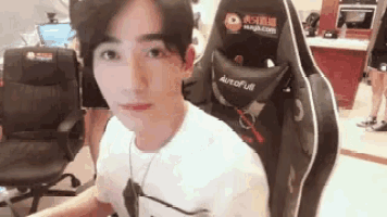 a young man is sitting in a black and white autofull gaming chair