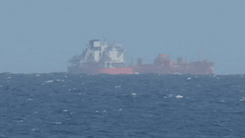 a large ship in the middle of the ocean with a clock on the side
