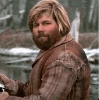 a man with a beard wearing a plaid shirt and a brown vest