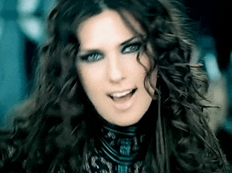 a close up of a woman 's face with long curly hair and blue eyes .