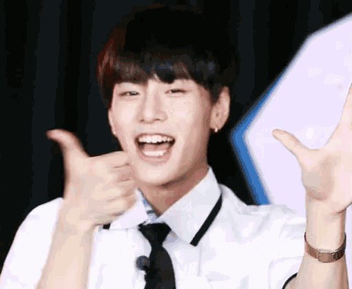 a young man wearing a white shirt and tie is giving a thumbs up sign .