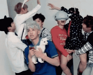 a group of young men are standing around a boy holding a stuffed animal