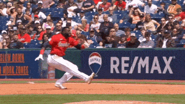 a baseball player is running on the field in front of a re / max ad