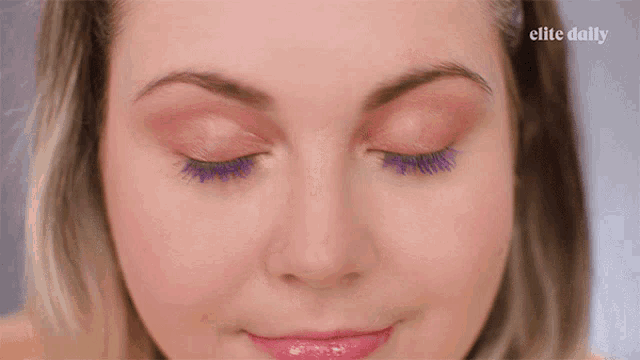 a close up of a woman 's face with the elite daily logo in the background