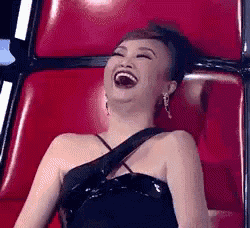 a woman is sitting in a red chair laughing .