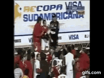 a group of people standing on top of each other in front of a sign that says copa sudamericana .