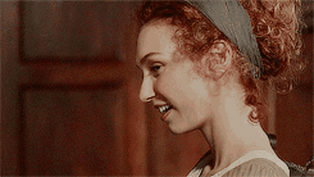 a woman with curly hair wearing a headband smiles