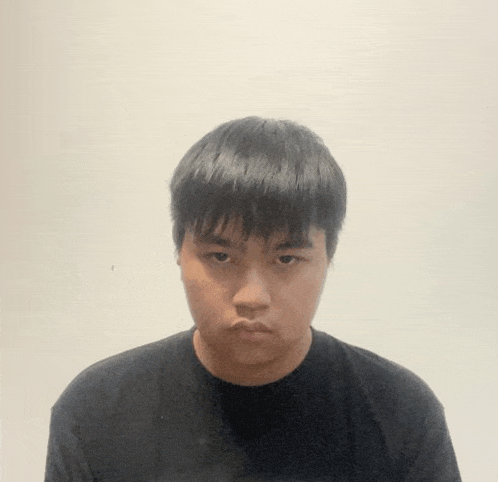 a young man wearing a black shirt is looking at the camera .