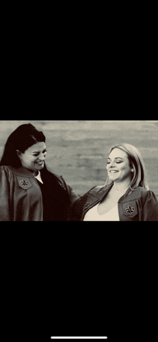 a black and white photo of two women in graduation gowns smiling