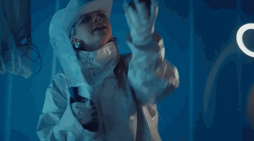 a woman in a white jacket and cowboy hat is holding a bottle