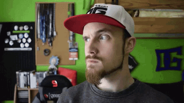 a man with a beard wearing a red and white hat with the letters ae on it