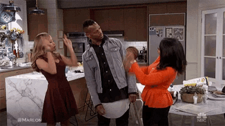 a man and two women are standing in a kitchen having a fight .