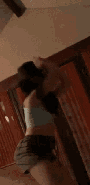 a woman in a crop top and shorts is standing in front of a door .