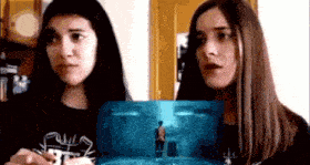 two women are standing next to each other and looking at a picture of a man .