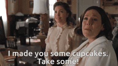 two women are sitting next to each other and one of them says " i made you some cupcakes "