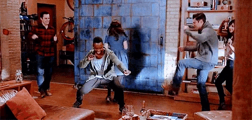 a group of people are dancing in a living room with a blue door in the background .