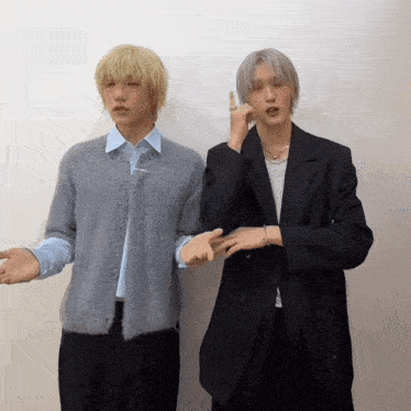 two men standing next to each other one wearing a sweater and the other a suit