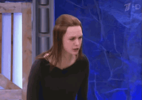 a woman in a black shirt is standing in front of a blue wall with the number 7 on it