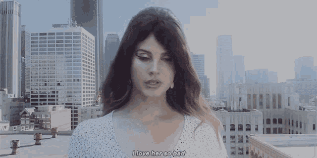 a woman says i love her so bad while standing in front of a city skyline